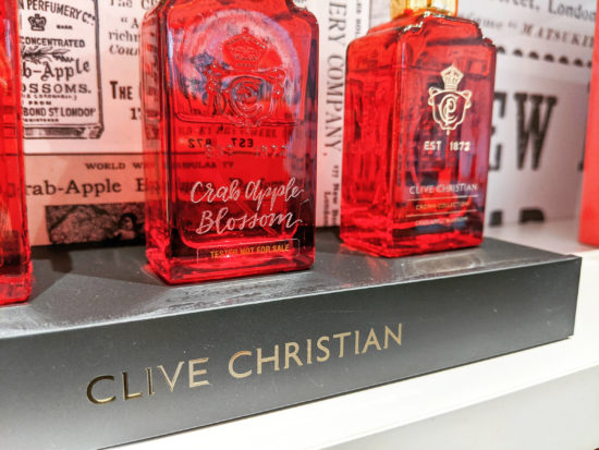 Hand glass engraving of the fragrance name 'Crab Apple Blossom' on a red perfume bottle.