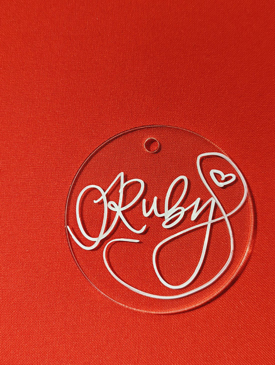 Personalized ornament for Ruby written in white ink on a clear circular-shaped acrylic ornament.